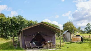 Safarizelt mit privater Dusche und Whirlpool bei Feather Down Pant y March Farm, Großbritannien, auf Wiese.
