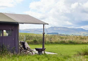 Safari-telt ved Feather Down Pant y March Farm i Storbritannien med udsigt over grønne marker og bakker.