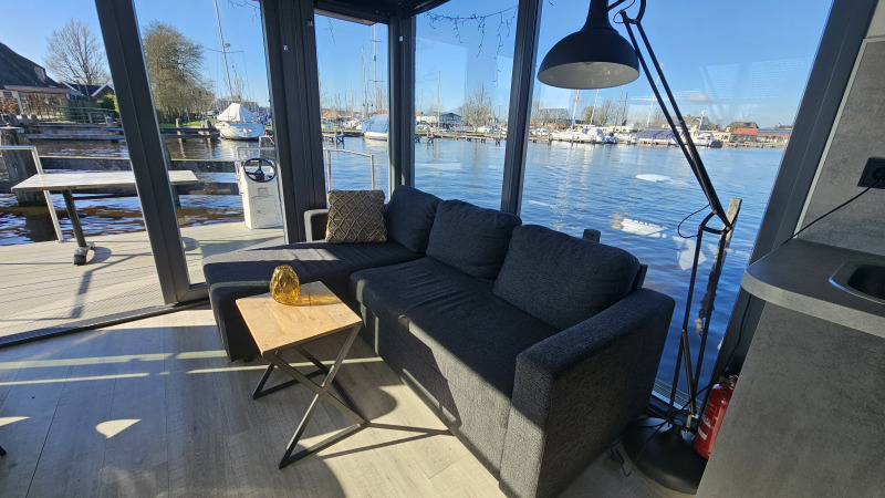 Sala de estar en Houseboat Heeg en Marina Heeg, Países Bajos, con vistas al agua y al puerto.