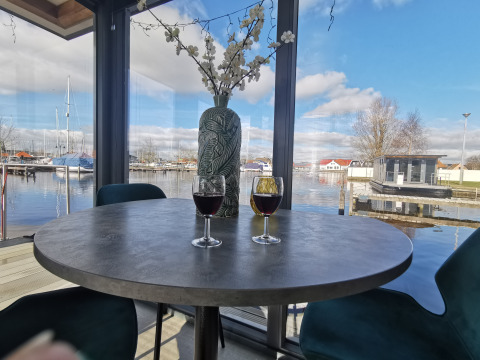 Vista desde Houseboat Heeg en la Marina Heeg en Países Bajos con dos copas de vino y vista al puerto.