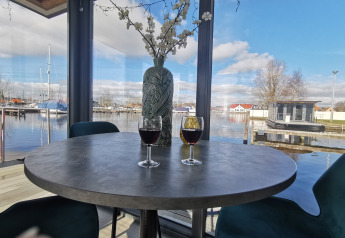 View from Houseboat Heeg at Marina Heeg in the Netherlands with two glasses of wine and a harbor view.