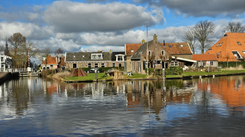 Husene og kanalen ved Houseboat Heeg i Marina Heeg, Holland, under en skyet og solrig himmel.