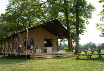 Safari tent with private bathroom and extra-large terrace at Holiday Park Mölke in the Netherlands, surrounded by trees.
