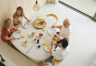 Cuatro personas disfrutan de un desayuno en la Lodge, sentados alrededor de una mesa con jugo y frutas.