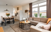 Lichte en moderne lodge met hoekbank, eettafel, grote ramen en toegang tot het terras.
