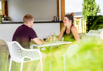 Dos personas disfrutan bebidas en una mesa exterior en la lodge Biebosch del Resort Mooi Bemelen, Países Bajos.