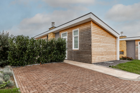 Lodge moderno de madera Biebosch en Resort Mooi Bemelen, Países Bajos, con entrada de adoquines y vegetación.