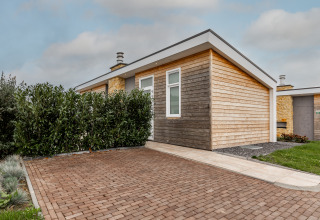 Lodge moderno de madera Biebosch en Resort Mooi Bemelen, Países Bajos, con entrada de adoquines y vegetación.