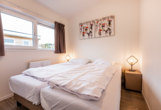 Acogedor dormitorio de lodge con cama doble, mesitas, lámparas modernas y ventana con cortinas.