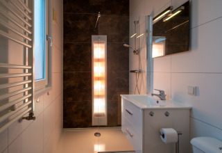 Baño moderno con ducha, lavabo y espejo en Biebosch - Sunshower, Resort Mooi Bemelen, Países Bajos.