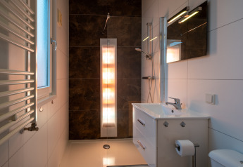 Baño moderno con ducha, lavabo y espejo en Biebosch - Sunshower, Resort Mooi Bemelen, Países Bajos.