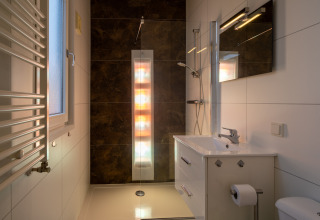 Baño moderno con ducha solar y decoración elegante en Biebosch - Sunshower, Resort Mooi Bemelen, Países Bajos.