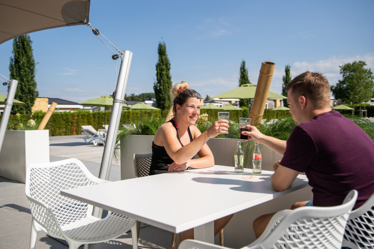 Two people enjoy drinks together at an outdoor table at Resort Mooi Bemelen in the Netherlands.