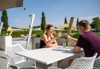 Twee mensen genieten samen van een drankje aan een buitentafel bij Resort Mooi Bemelen in Nederland.