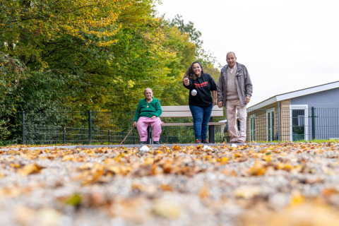 Tres personas juegan petanca al aire libre en otoño en Biebosch - Sunshower, Resort Mooi Bemelen, Países Bajos.