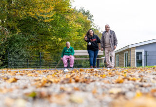 Tres personas juegan petanca al aire libre en otoño en Biebosch - Sunshower, Resort Mooi Bemelen, Países Bajos.