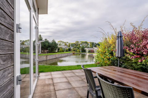 Uitzicht vanop het terras van lodge Biebosch - Sunshower aan Resort Mooi Bemelen, met vijver en groen.