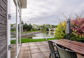 Uitzicht vanop het terras van lodge Biebosch - Sunshower aan Resort Mooi Bemelen, met vijver en groen.