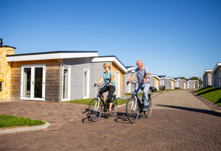 Dos personas andando en bicicleta frente a la Biebosch - Sunshower lodge en Resort Mooi Bemelen, Países Bajos.