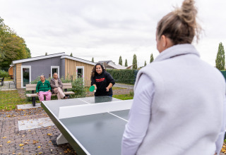 Dos mujeres juegan tenis de mesa al aire libre en Biebosch - Sunshower del Resort Mooi Bemelen, Países Bajos.
