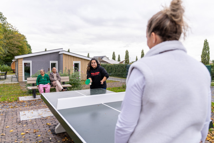 Dos mujeres juegan tenis de mesa al aire libre en Biebosch - Sunshower del Resort Mooi Bemelen, Países Bajos.