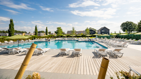 Piscina al aire libre con tumbonas y sombrillas en el Resort Mooi Bemelen, Países Bajos, en un día soleado.