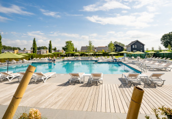 Udendørs swimmingpool med liggestole og parasoller på Resort Mooi Bemelen i Holland under en blå himmel.