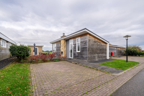 Moderne træhytte ved Resort Mooi Bemelen i Nederlandene med brostensbelagt terrasse og grønne omgivelser.