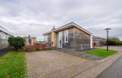Moderne træhytte ved Resort Mooi Bemelen i Nederlandene med brostensbelagt terrasse og grønne omgivelser.
