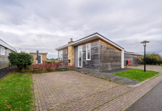 Moderne træhytte ved Resort Mooi Bemelen i Nederlandene med brostensbelagt terrasse og grønne omgivelser.