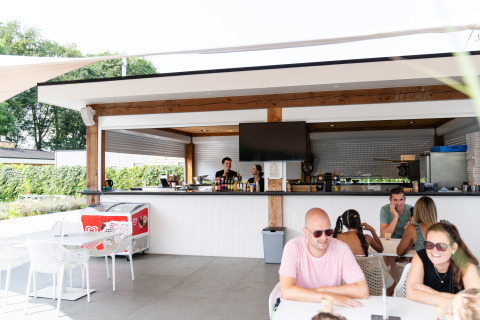 Bar y zona de comedor al aire libre en Biebosch - tuinhuis, Resort Mooi Bemelen, con huéspedes relajados.