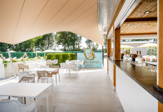 Zona lounge exterior con mesas y sillas junto a Funky Buddha Pool en Resort Mooi Bemelen, Países Bajos.