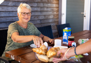 Mujer mayor desayunando al aire libre en Biebosch - tuinhuis, Resort Mooi Bemelen, Países Bajos.