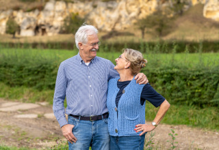 Pareja mayor sonriendo al aire libre en Biebosch - tuinhuis, Resort Mooi Bemelen, Países Bajos.