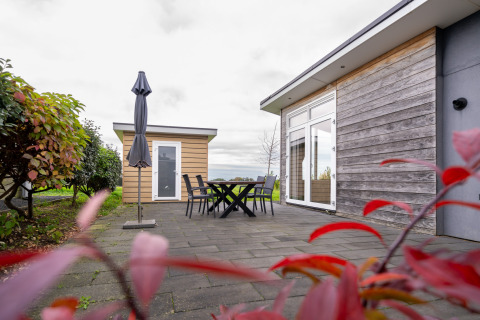 Terrasse extérieure avec table, chaises et parasol devant un lodge en bois au Resort Mooi Bemelen aux Pays-Bas.