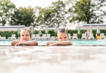 Due bambini si rilassano al bordo della piscina a Biebosch - tuinhuis, Resort Mooi Bemelen, Paesi Bassi, estate.