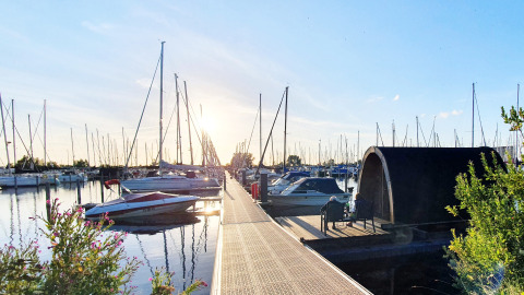 Coucher de soleil sur la marina, tiny house, bateaux et personnes à Marina Parcs Almere, Pays-Bas.