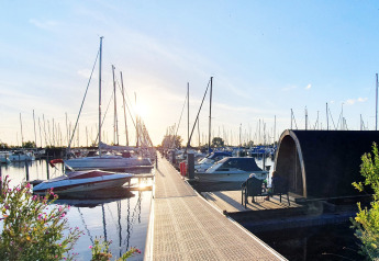 Sunset view of marina, tiny house, boats, and people relaxing at Marina Parcs Almere in the Netherlands.