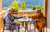 Pareja mayor disfrutando vino en la terraza de Enzian Waterfront, Ossiacher See, Austria, con vistas al lago.