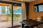 Moderne lodge met houten muur, grote tafel en schuifdeur naar terras aan Ossiacher See in Oostenrijk.