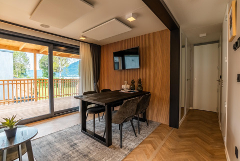 Moderne eetkamer met grote ramen en zicht op het balkon in Enzian Waterfront, Ossiacher See, Oostenrijk.