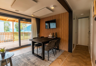 Modern dining area with large windows and balcony view at Enzian Waterfront lodge, Ossiacher See, Austria.