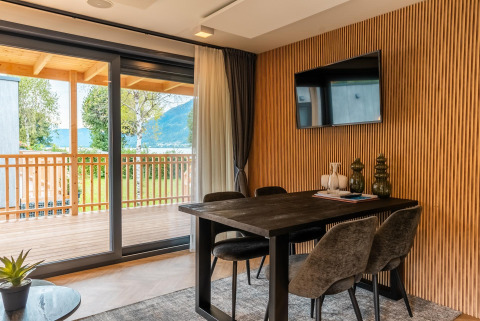 Woonruimte met eettafel, stoelen en balkonzicht in Enzian Waterfront aan de Ossiacher See in Oostenrijk.
