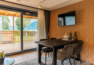 Comedor moderno con mesa, sillas y balcón en Enzian Waterfront junto al lago Ossiacher See, Austria.
