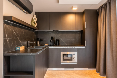 Moderne kitchenette bij Enzian Waterfront aan de Ossiacher See in Oostenrijk met zwarte kasten en marmerwand.