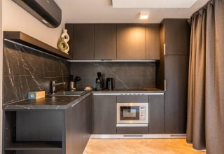 Moderne kitchenette bij Enzian Waterfront aan de Ossiacher See in Oostenrijk met zwarte kasten en marmerwand.