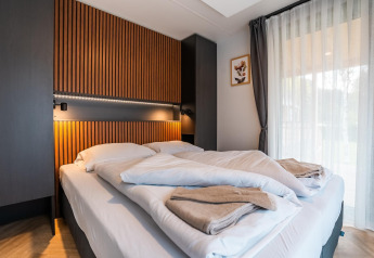 Dormitorio moderno con paneles de madera en Enzian Waterfront lodge junto al lago Ossiacher See, Austria.
