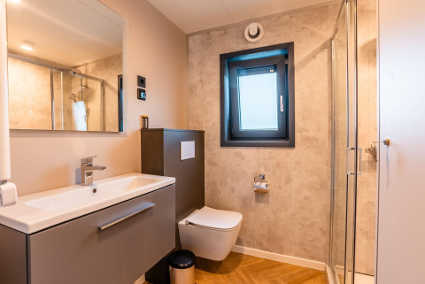 Baño moderno en Enzian Waterfront en Ossiacher See, Austria, con ducha, inodoro y ventana.