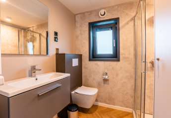 Salle de bain moderne à Enzian Waterfront près du lac Ossiacher See en Autriche, avec douche et fenêtre.