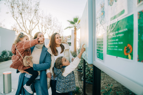 Familia observa un panel informativo en Camping Costa del Sol Glamping Village, Andalucía, España.